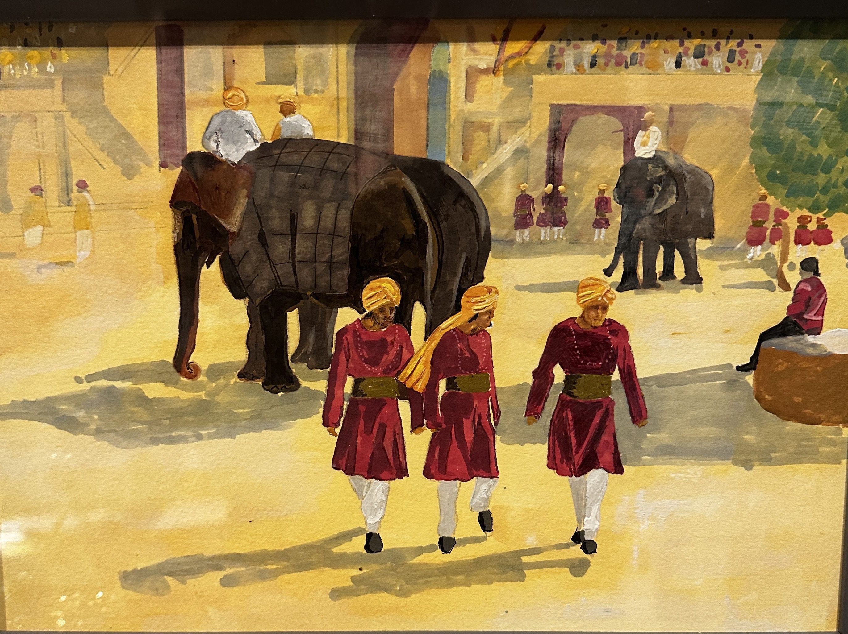 Three children in red robes walking in a historic setting with elephants.