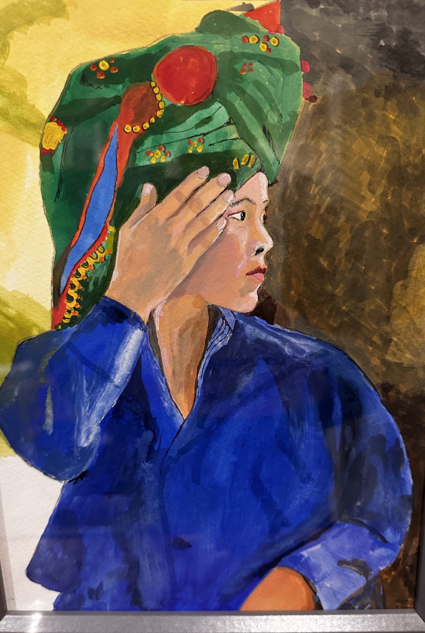 A woman in a blue garment adjusts her hair with a colorful headscarf.