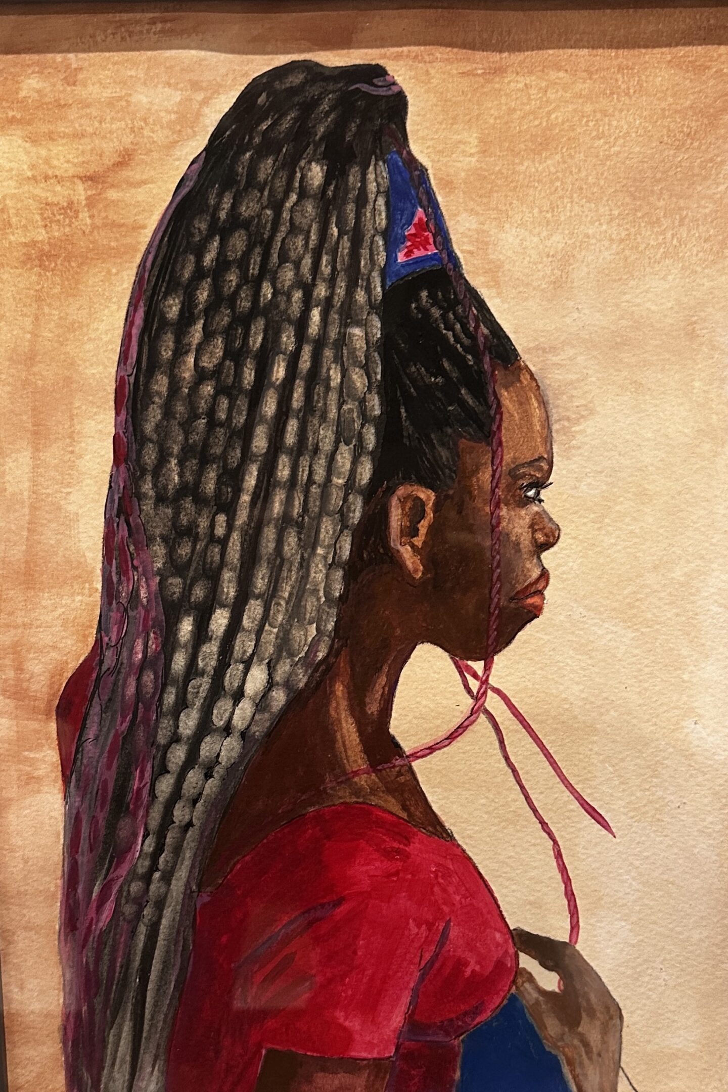 Profile of a woman with intricate braided hair and a red outfit.