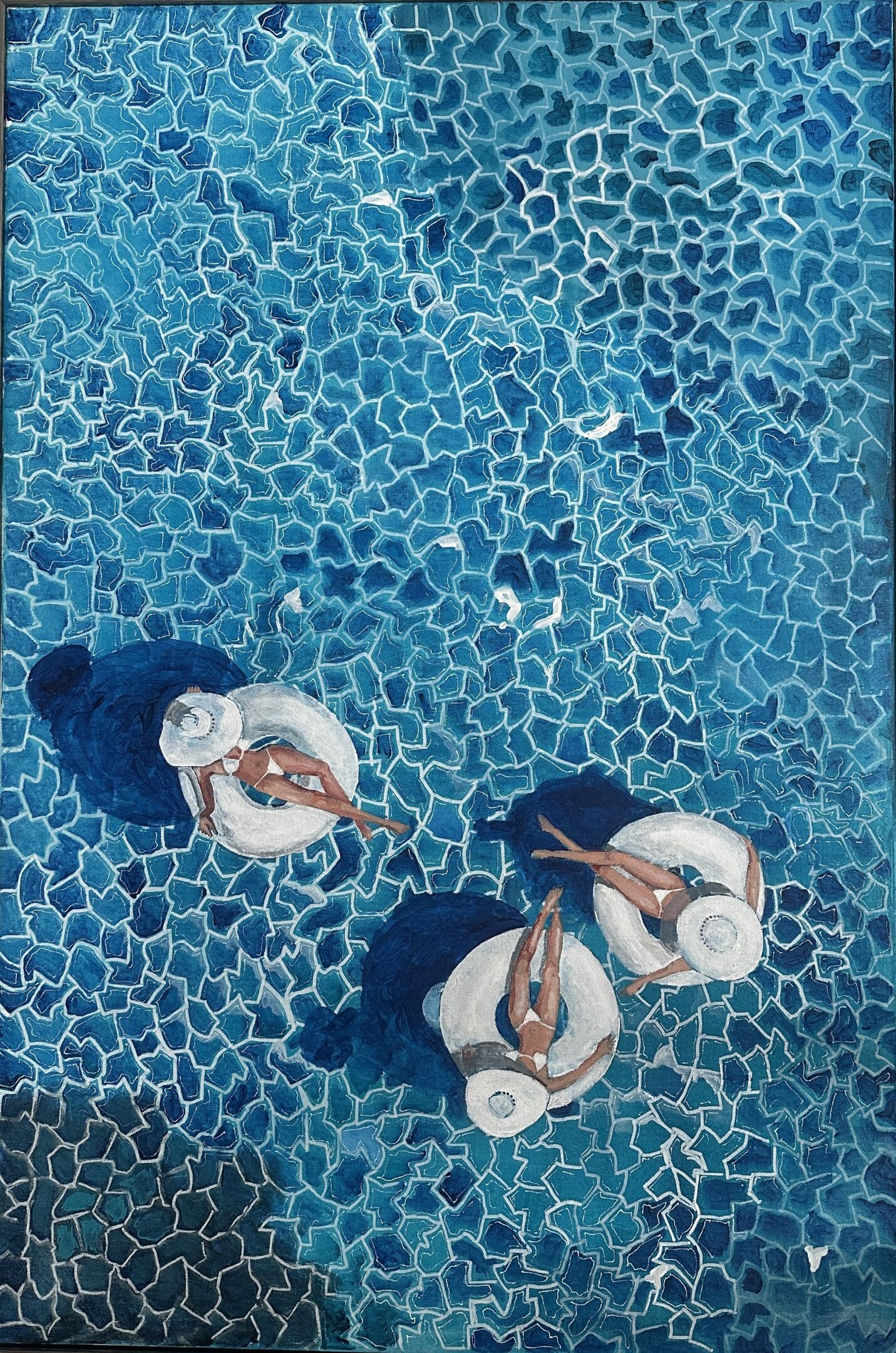 Three people relaxing on pool floats in a blue pool.
