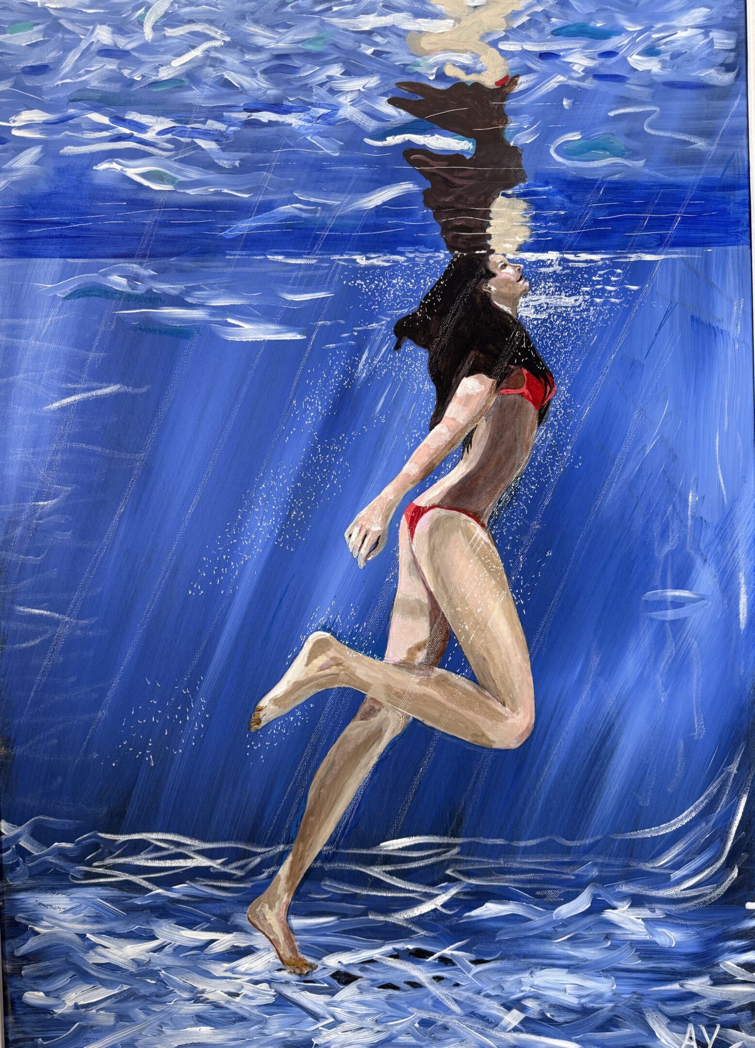 A person swimming underwater in a blue pool.