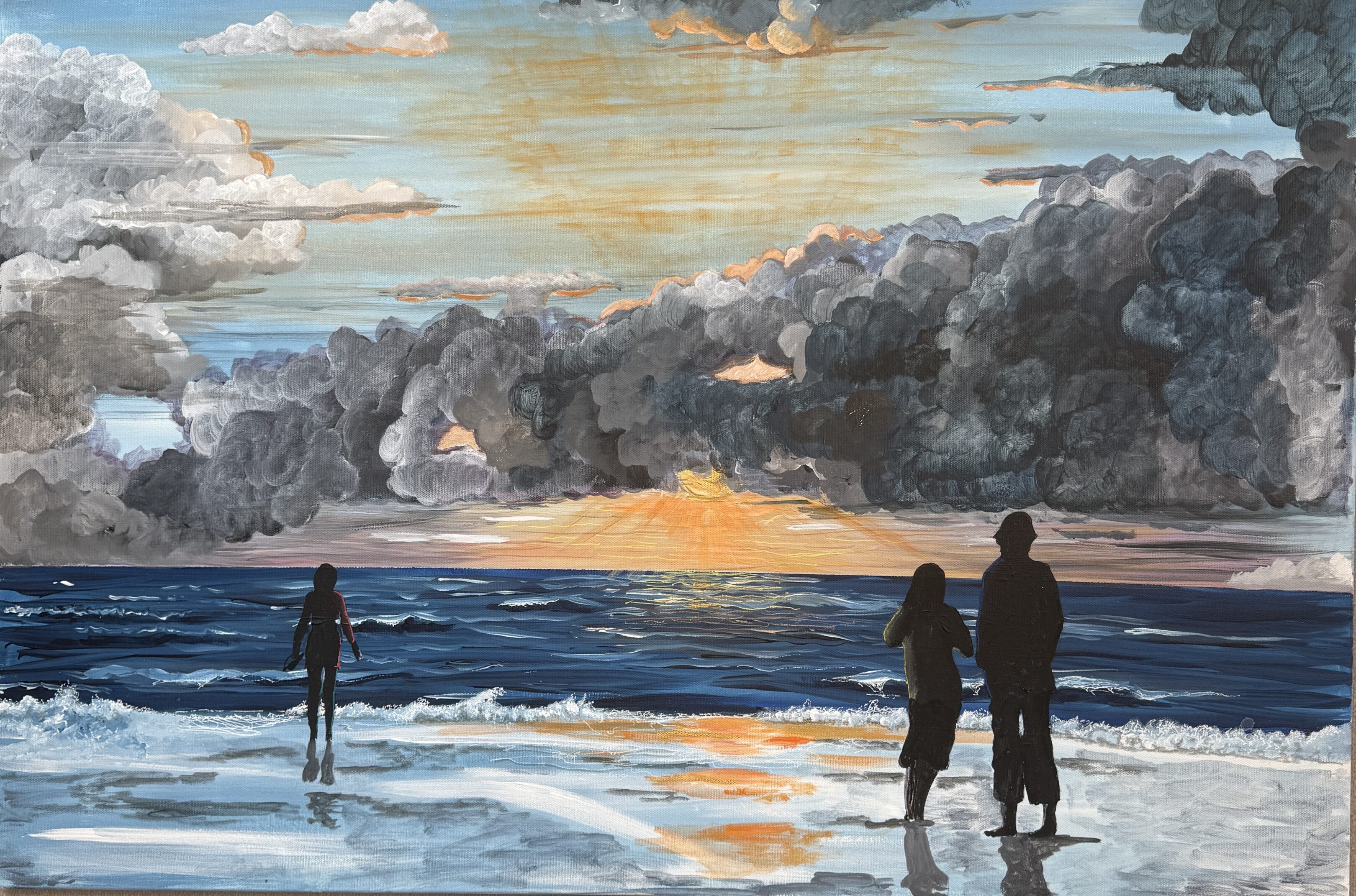 Silhouettes of people on a beach at sunset with dramatic clouds.