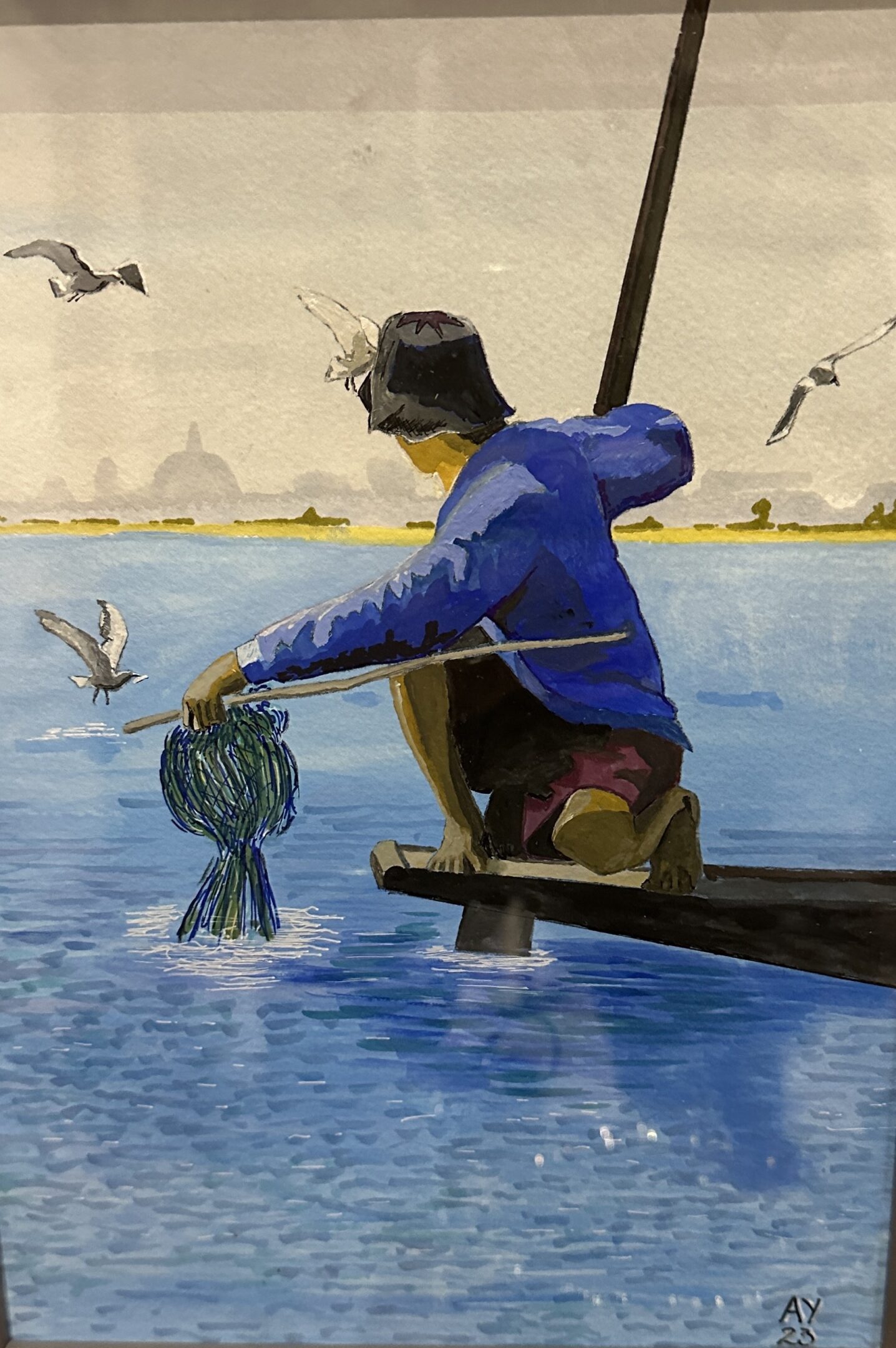 Fisherman in blue shirt pulling net from the water on a boat.