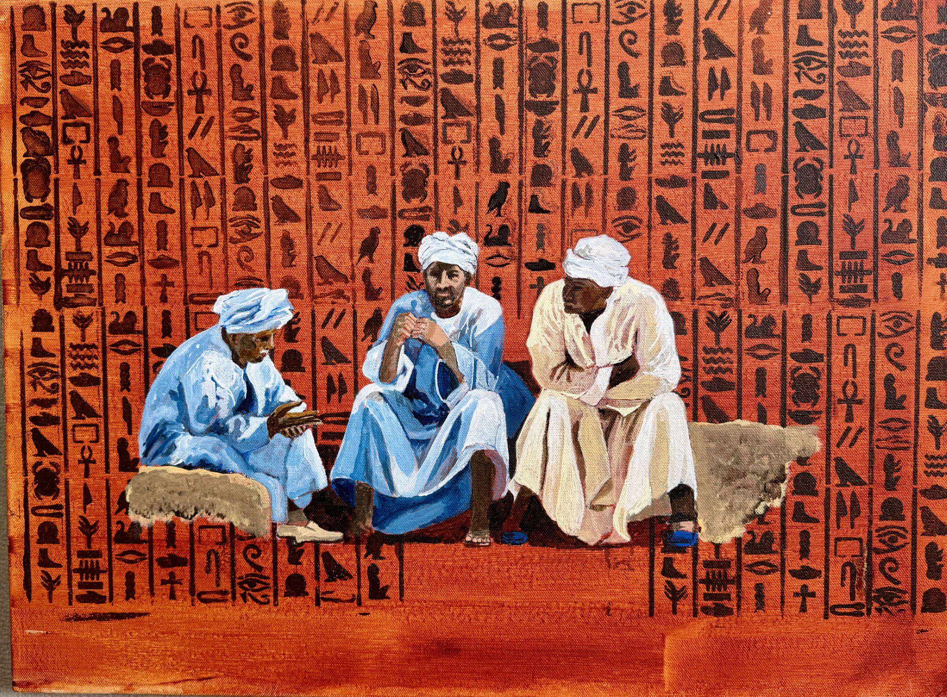 Three men in traditional attire sit and talk against a backdrop of hieroglyphics.